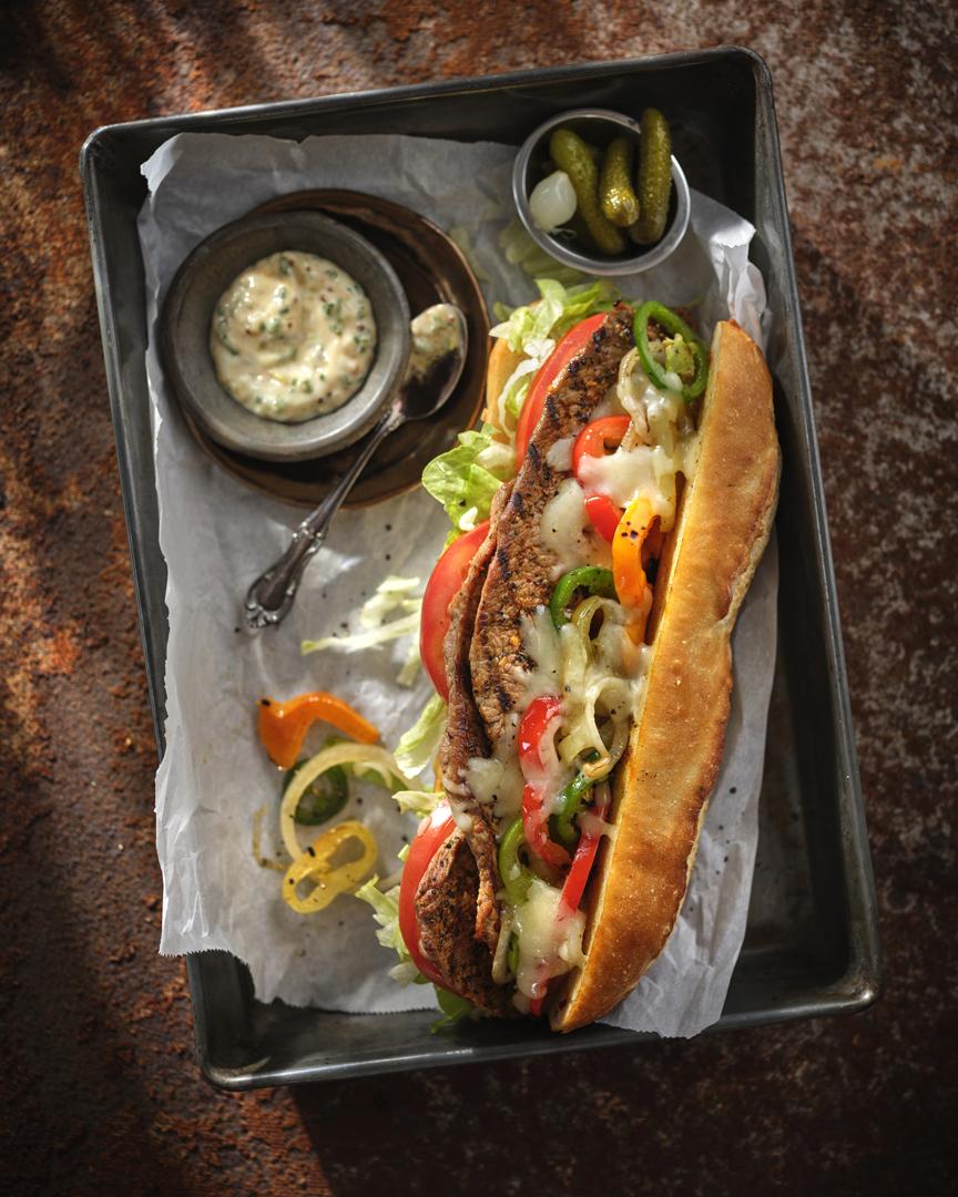 A thick cut veal loin chop resting on a pan of sauteed mushrooms.