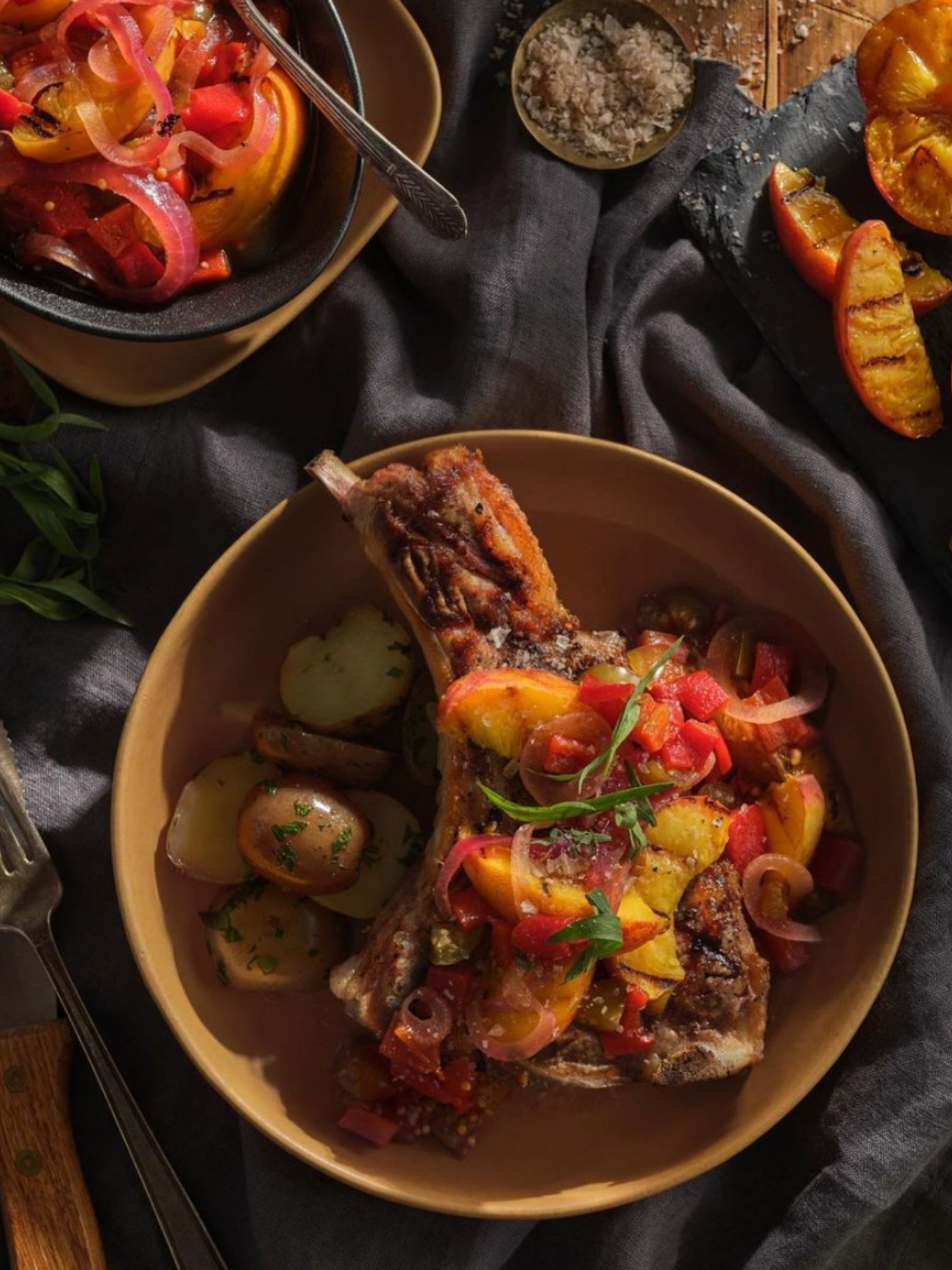 A thick cut veal loin chop resting on a pan of sauteed mushrooms.