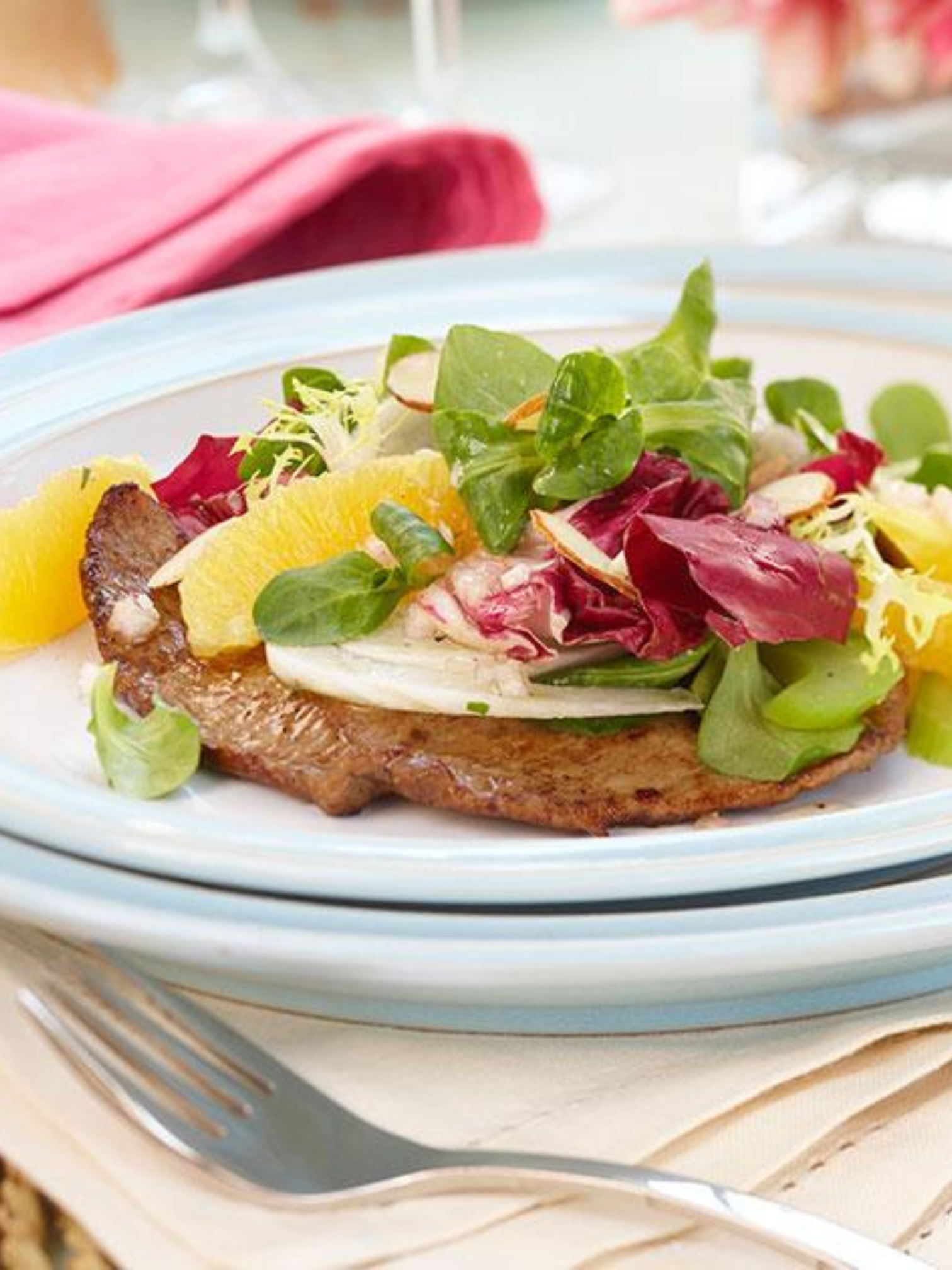 A thick cut veal loin chop resting on a pan of sauteed mushrooms.