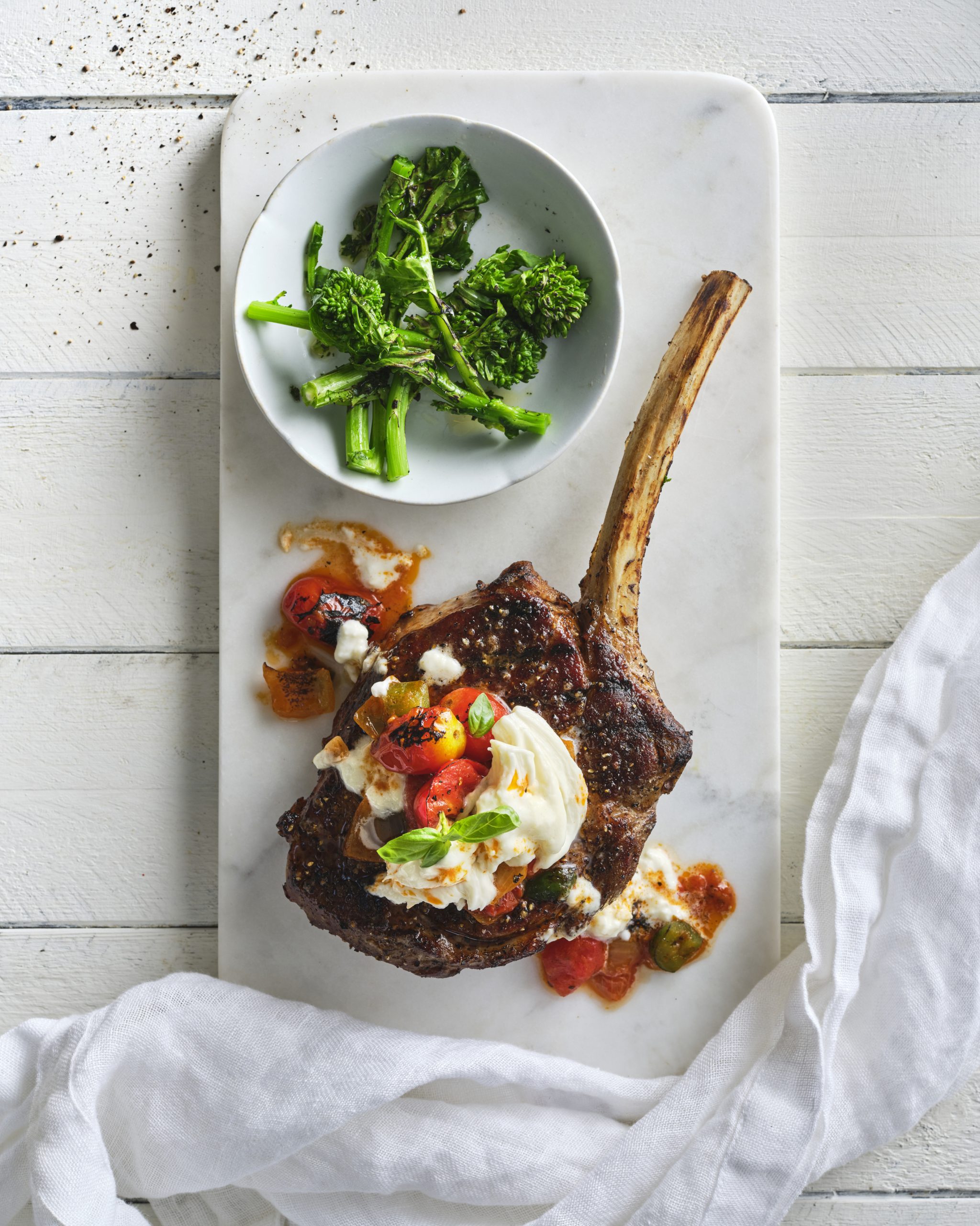 A thick cut veal loin chop resting on a pan of sauteed mushrooms.